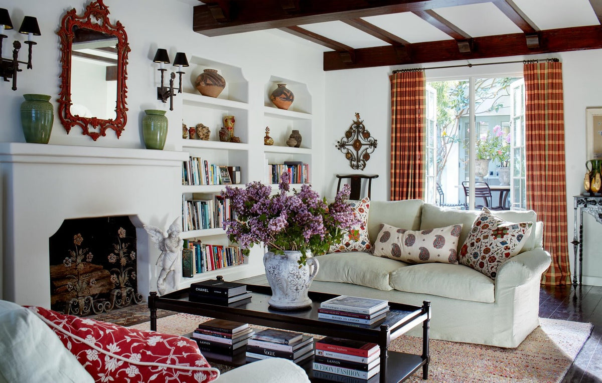 A bright, traditional living room with two white sofas with pillows in Kirkbean Red (Turquoise), in Abu Red, and in Safi Suzani, designed by Kathryn M. Ireland.