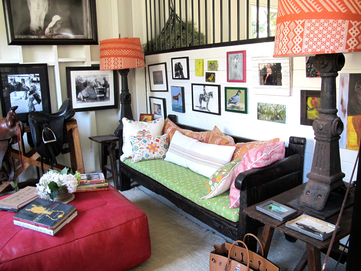 A dark wooden daybed with a Casablanca Margarita Green/Festive Orange cushion and Tangier Natural Flame/Natural lampshades designed by Kathryn M. Ireland