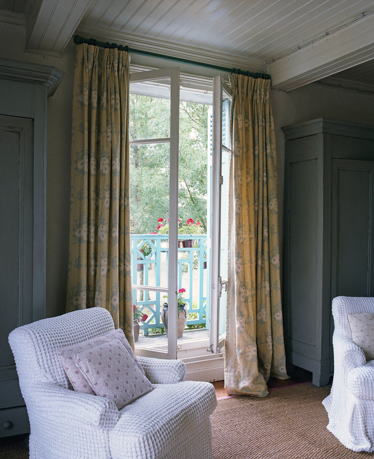 A pair of floor-length curtains in Floral Batik Yellow in a bedroom designed by Kathryn M. Ireland
