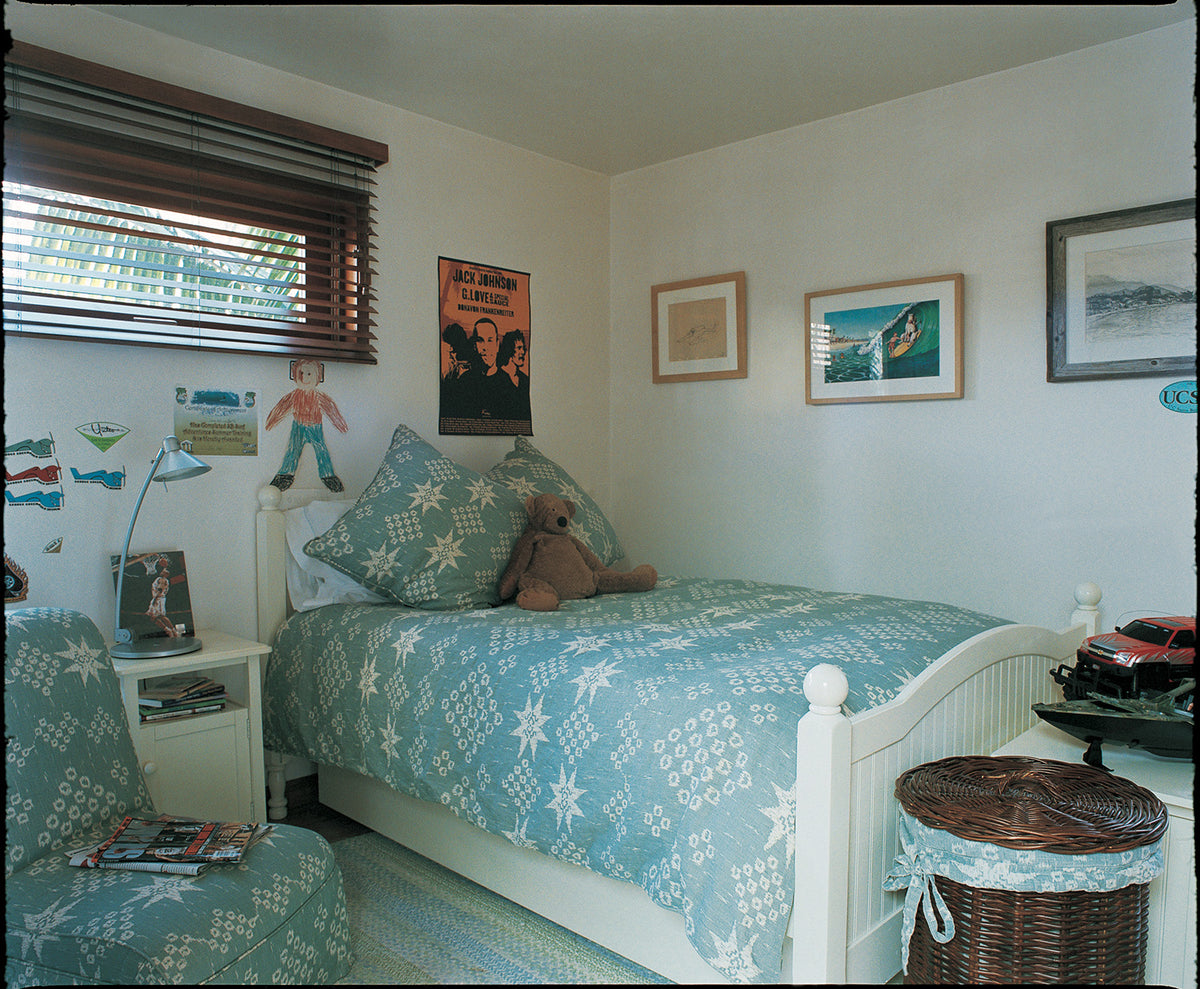 A children's bedroom with a Gitana Blue bedspread, pillows, and chair designed by Kathryn M. Ireland