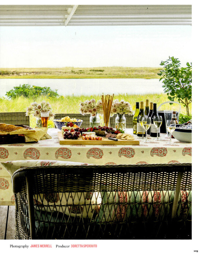 A page in House Beautiful magazine featuring a outdoor dining table in a Cape Cod home designed by Kathryn M. Ireland featuring a tablecloth in Kirkbean - Red (Turquoise)