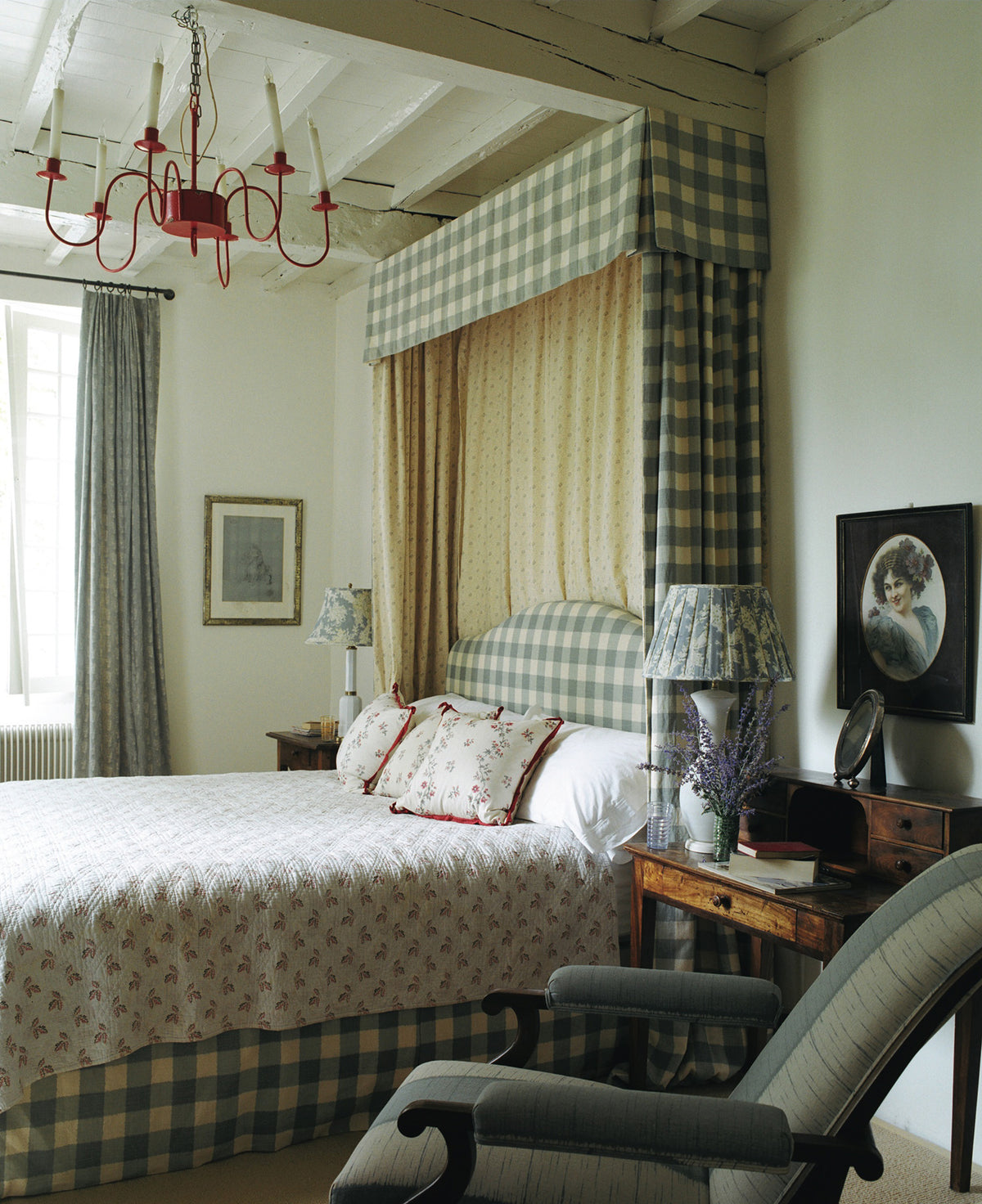 A bedroom featuring a bed with a Ikat Check Blue canopy and headboard, and a large upholstered armchair in Ikat Stripe Blue designed by Kathryn M. Ireland