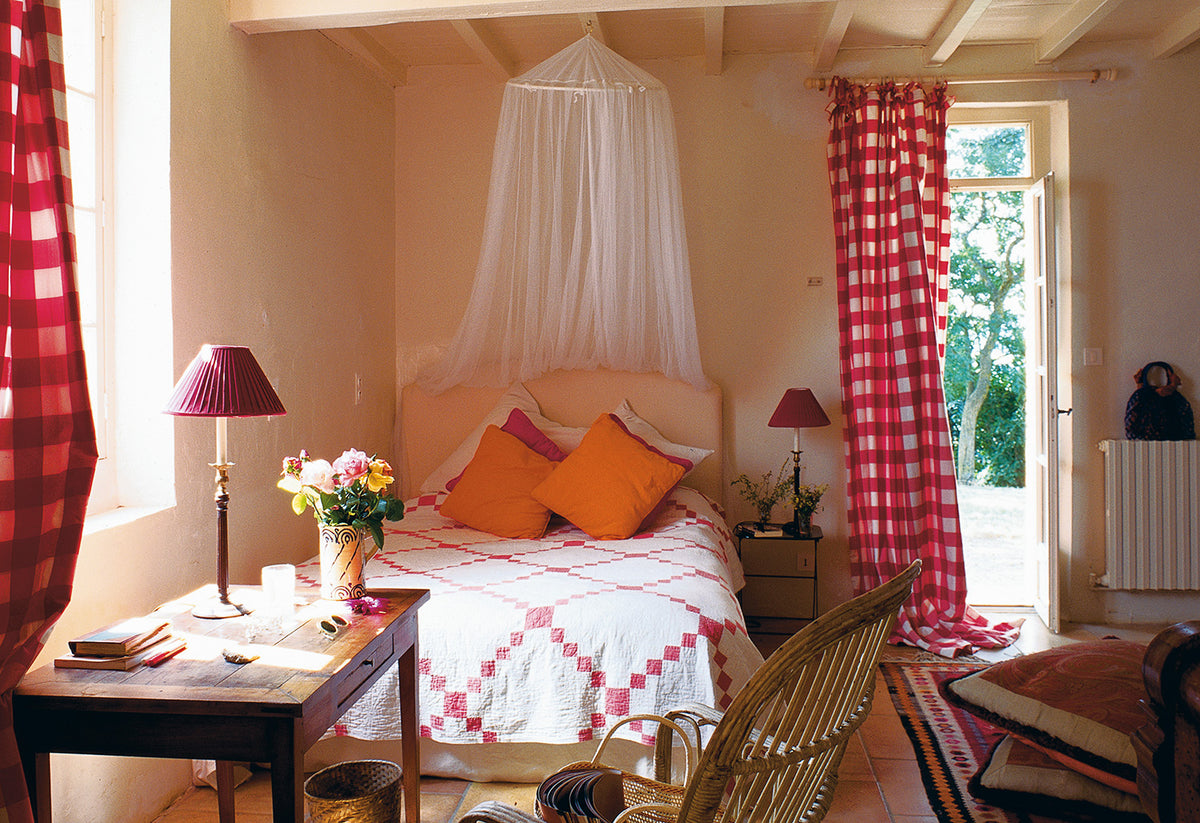 A cozy bedroom interior Ikat Check Red curtains designed by Kathryn M. Ireland