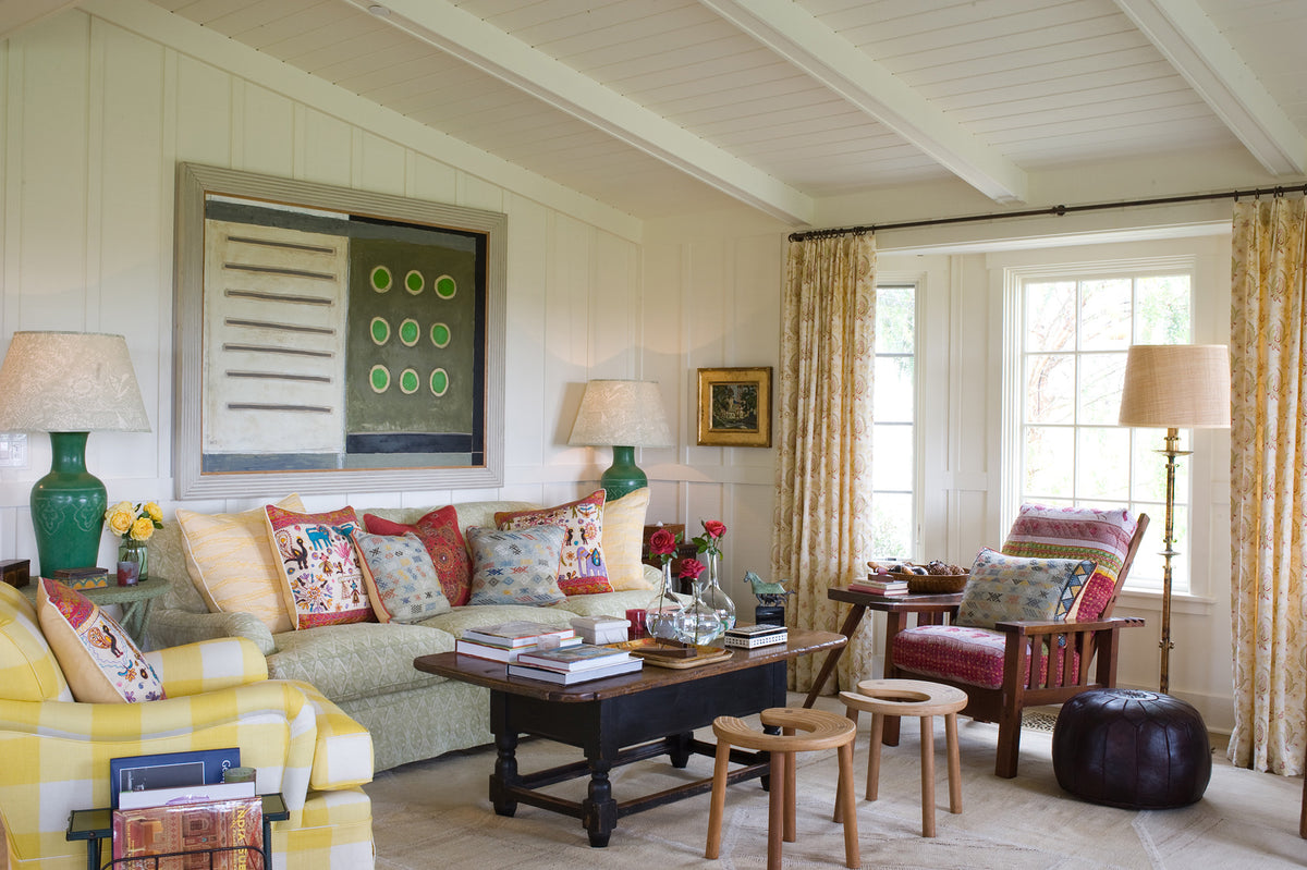 A living room featuring a sofa in Diamond Batik Blue, an arm chair in Ikat Check Yellow, curtains in Paisley Stripe Red designed by Kathryn M. Ireland