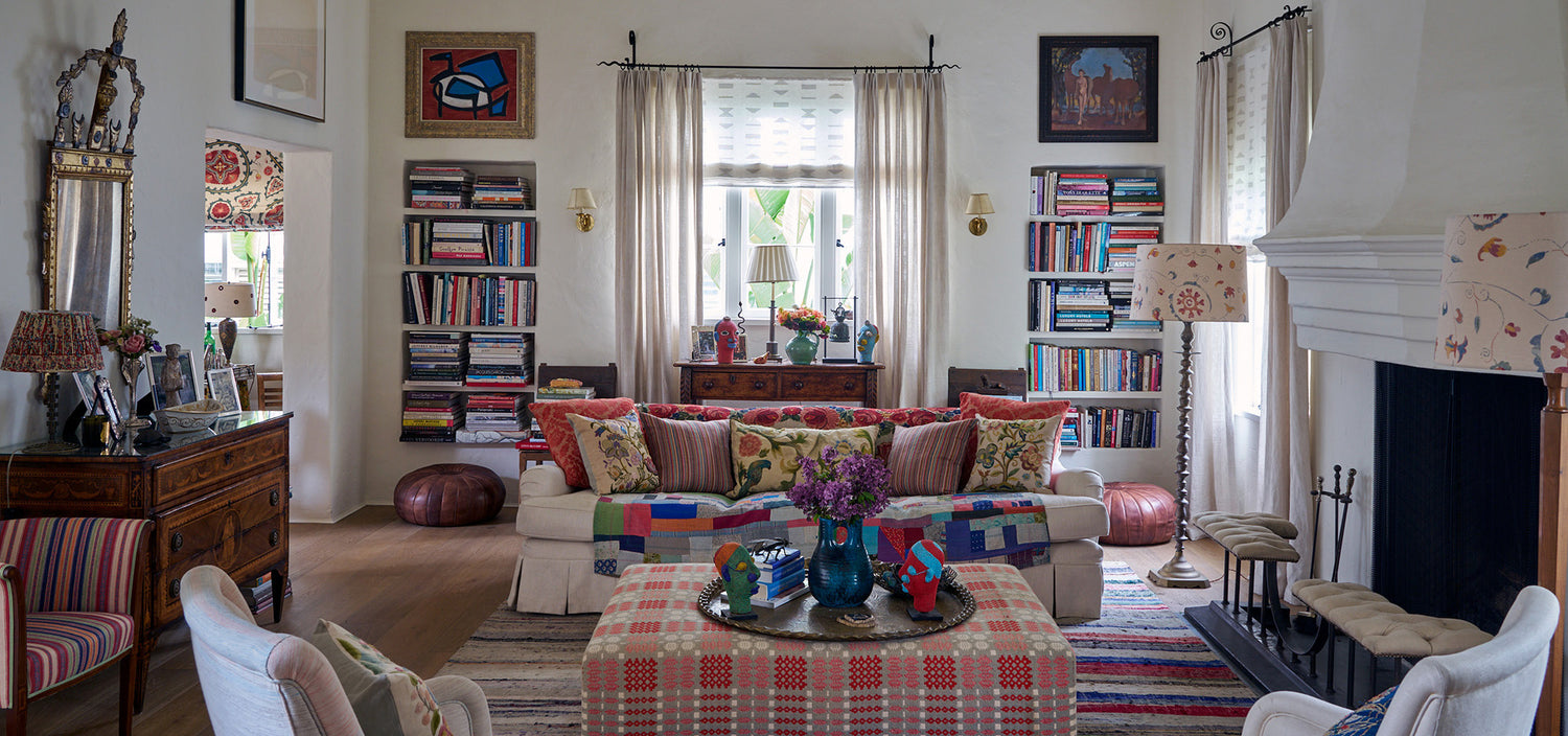 A living room designed by Kathryn M. Ireland featuring Kippford Stripe Multi pillows, Bukhara Suzani Multi on Oatmeal lampshades, Ottoman Stripe Royal Multi armchair, and Sultan Suzani Indigo window treatments.
