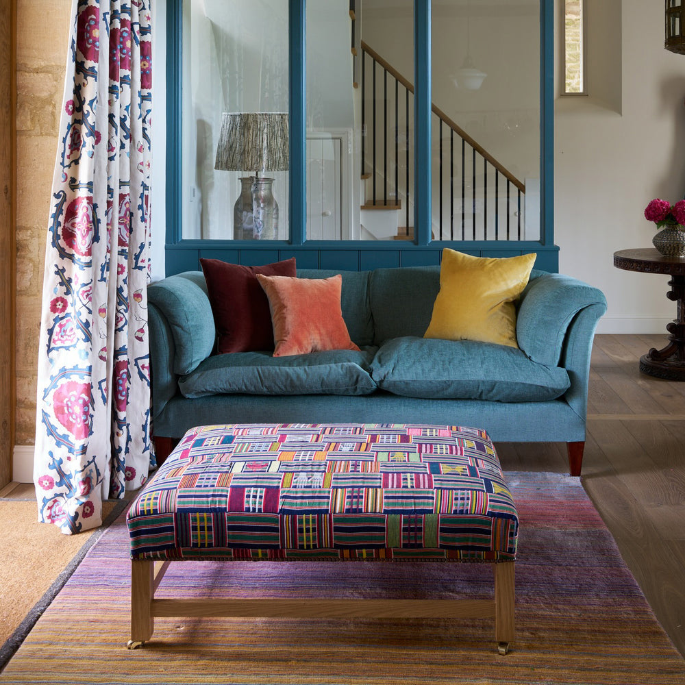 A teal velvet sofa in a room designed by Kathryn M. Ireland flanked by Sultan Suzani Indigo window drapes.