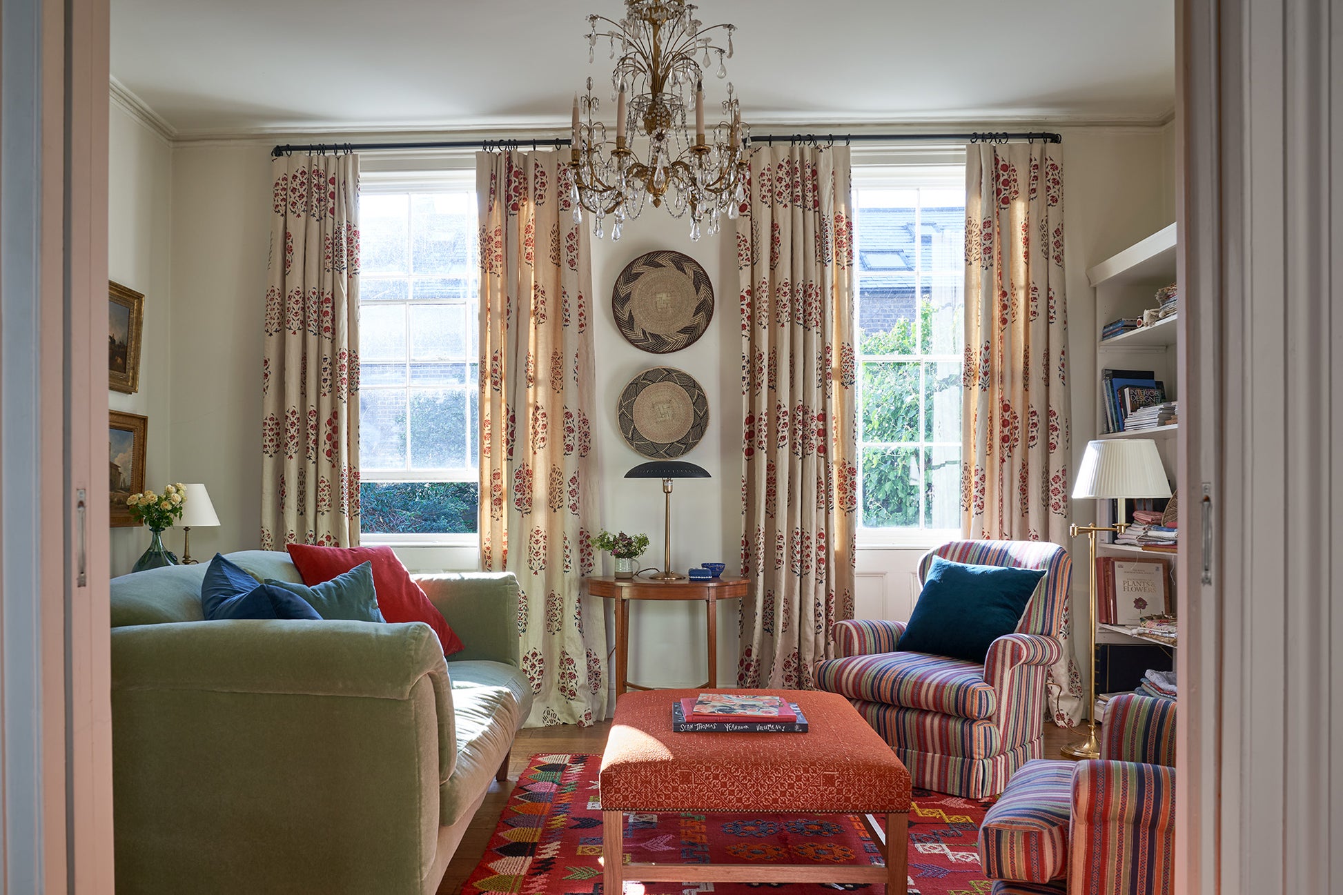 A living room with arm chairs in Ottoman Stripe Multi and curtains in Hilltop Paisley Regal designed by Kathryn M. Ireland