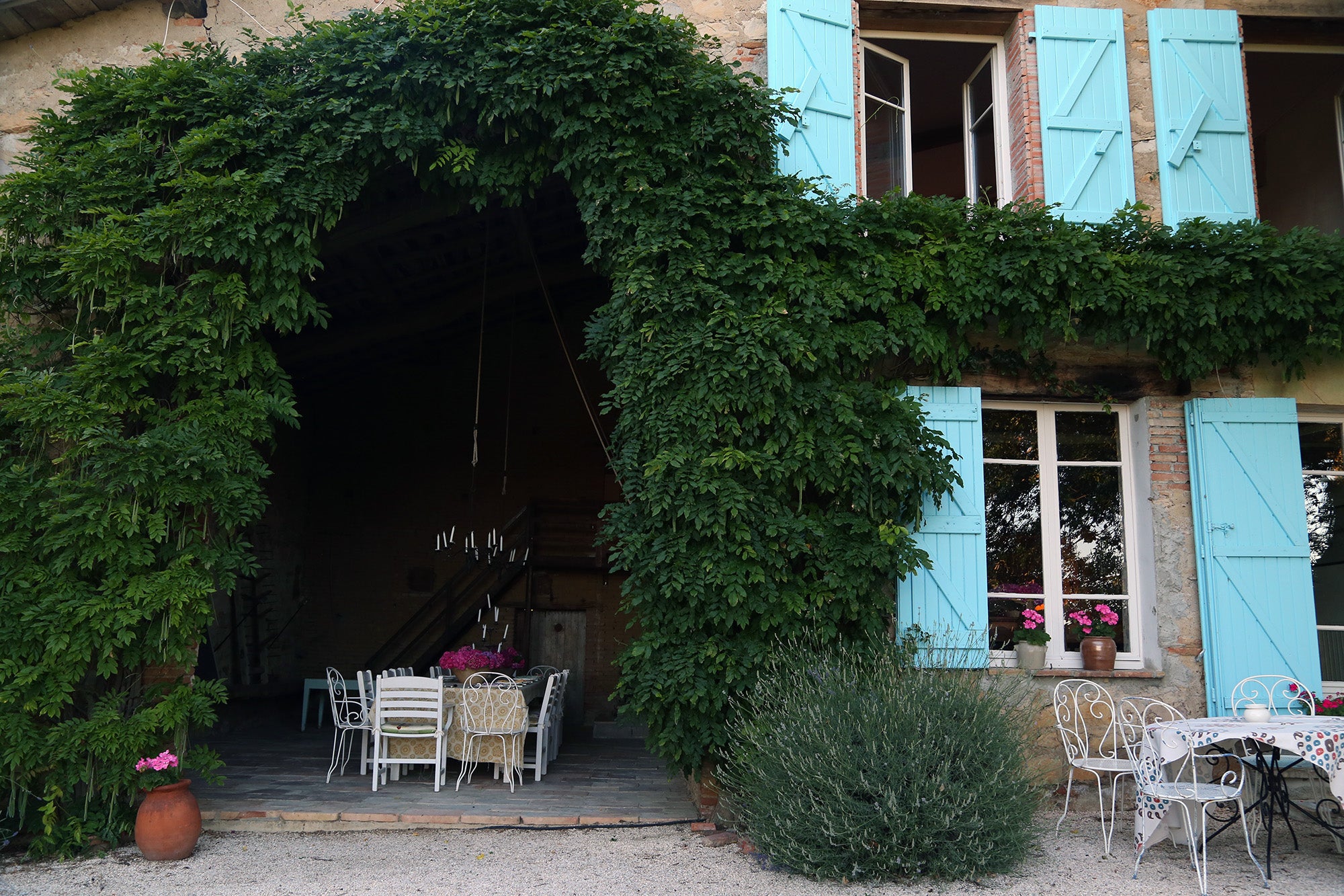 A dining table inside a rustic barn surrounded by an arch of vines at Kathryn M. Ireland's home in the south of France