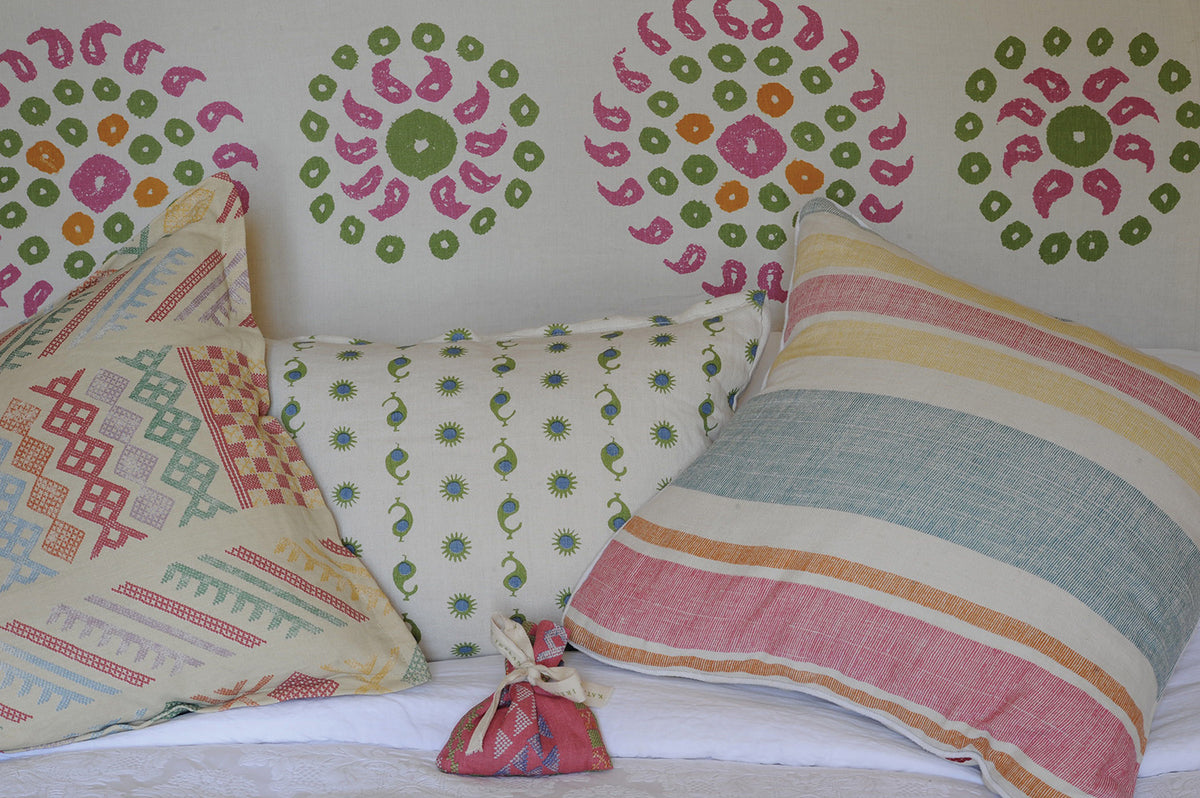 Pillows in Casablanca Natural Natural/Margarita Green & Electric Blue, Moroccan Stripe, and Tangier Multi, in front of Marrakech Bubblegum Pink wallpaper designed by Kathryn M. Ireland