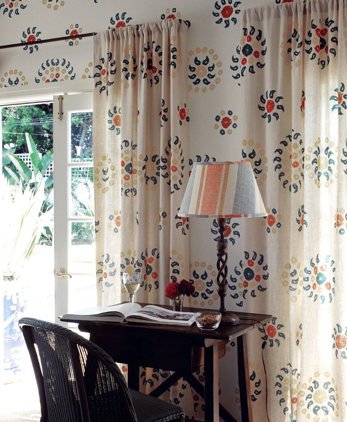 A bedroom with a pair of Natural Marrakech Natural/Teal curtains and Marrakech Teal wallpaper designed by Kathryn M. Ireland