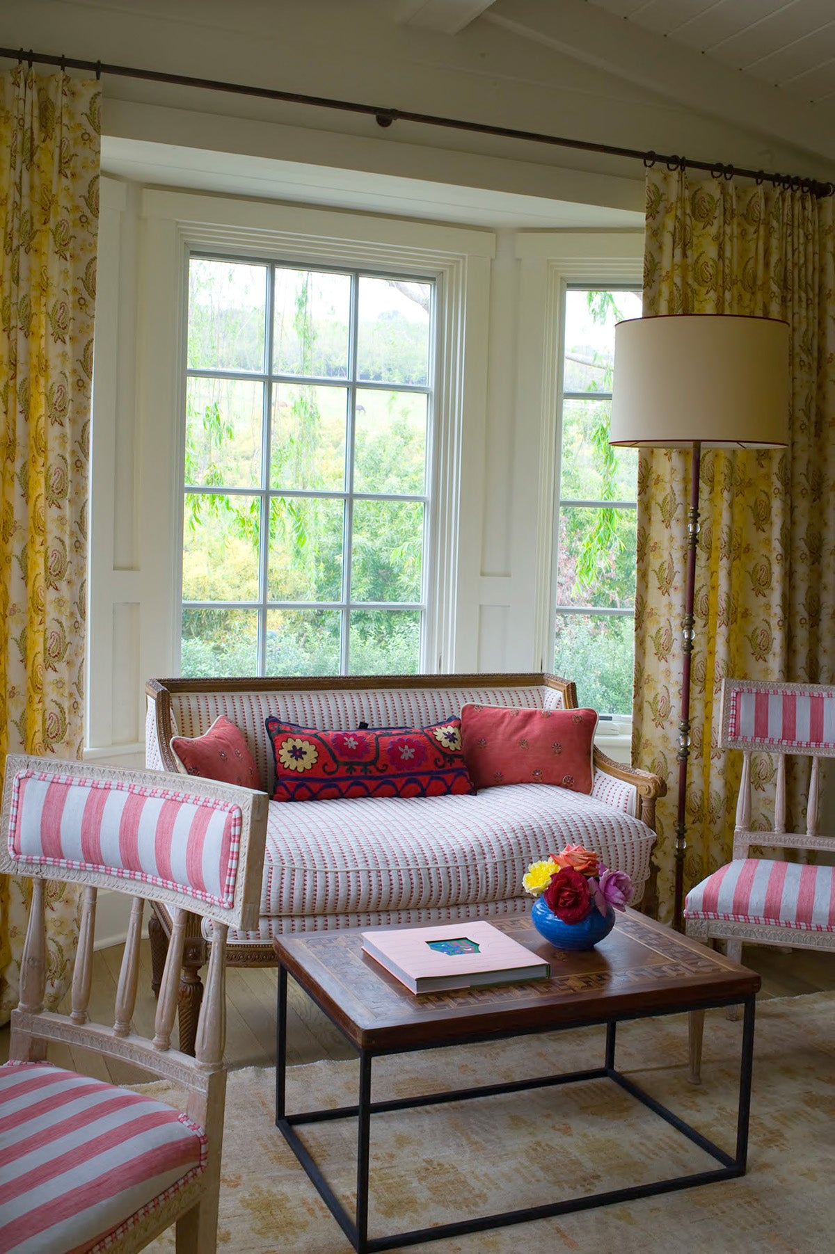 A cozy living room scene featuring a striped sofa with Paisley Stripe Red curtains designed by Kathryn M. Ireland