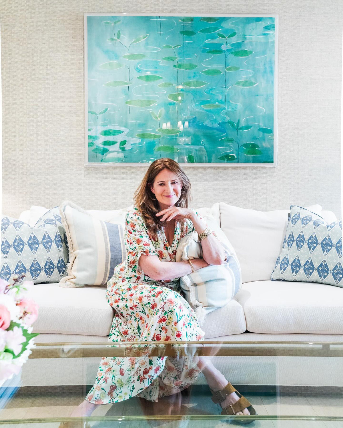 Kathryn M. Ireland sits on a sofa flanked by pillows in Diamond Batik Baby Blue and pillows in Moroccan Stripe Nautical fabric.