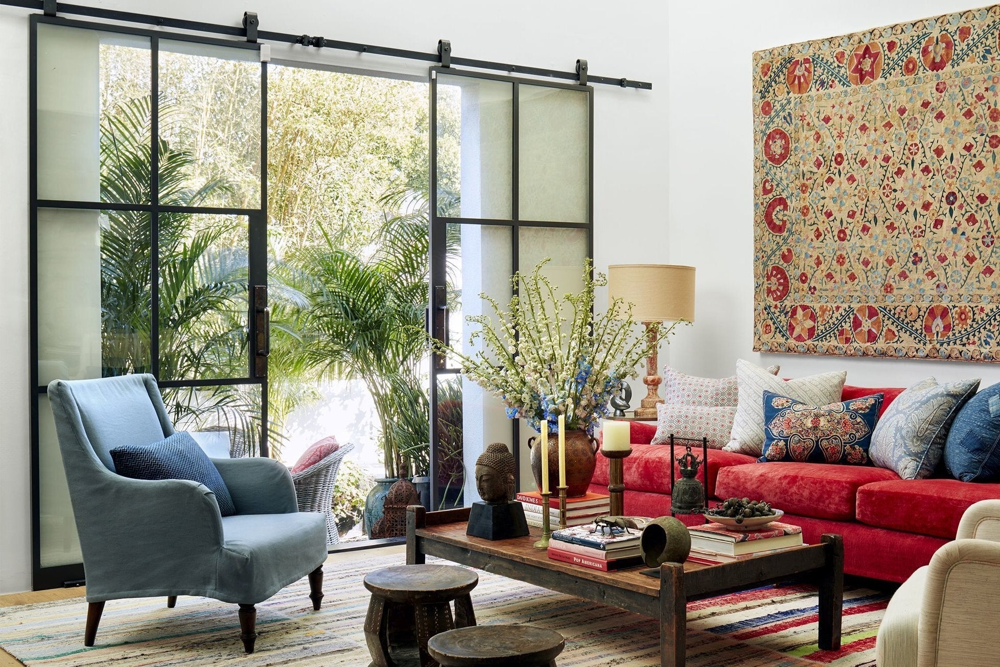 Living room designed by Kathryn M. Ireland with red sofa, blue armchair, and decorative elements.