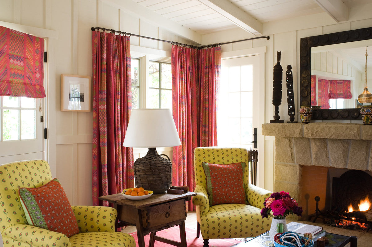 A living room featuring Tangier Multi Peony Multi curtains and roman shades, and Casablanca Yellow arm chairs.