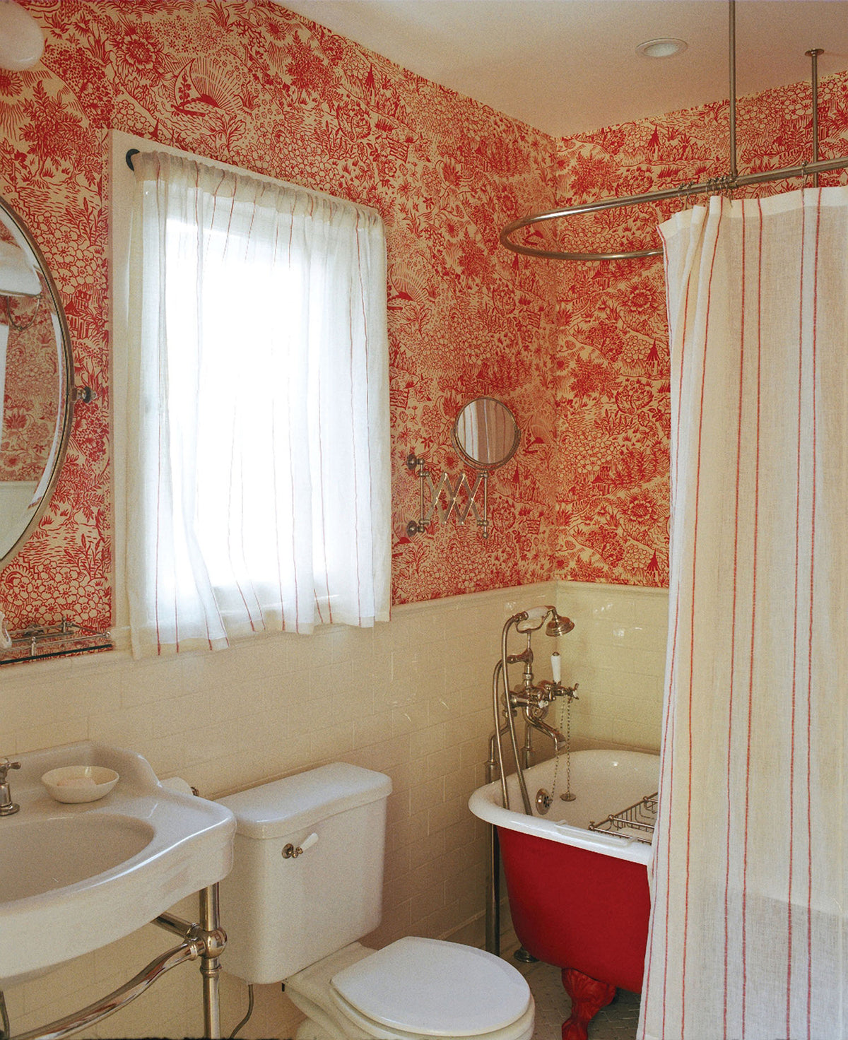 A bathroom featuring Toile Peony wallpaper and shower curtain in Sheer Stripe Red designed by Kathryn M. Ireland